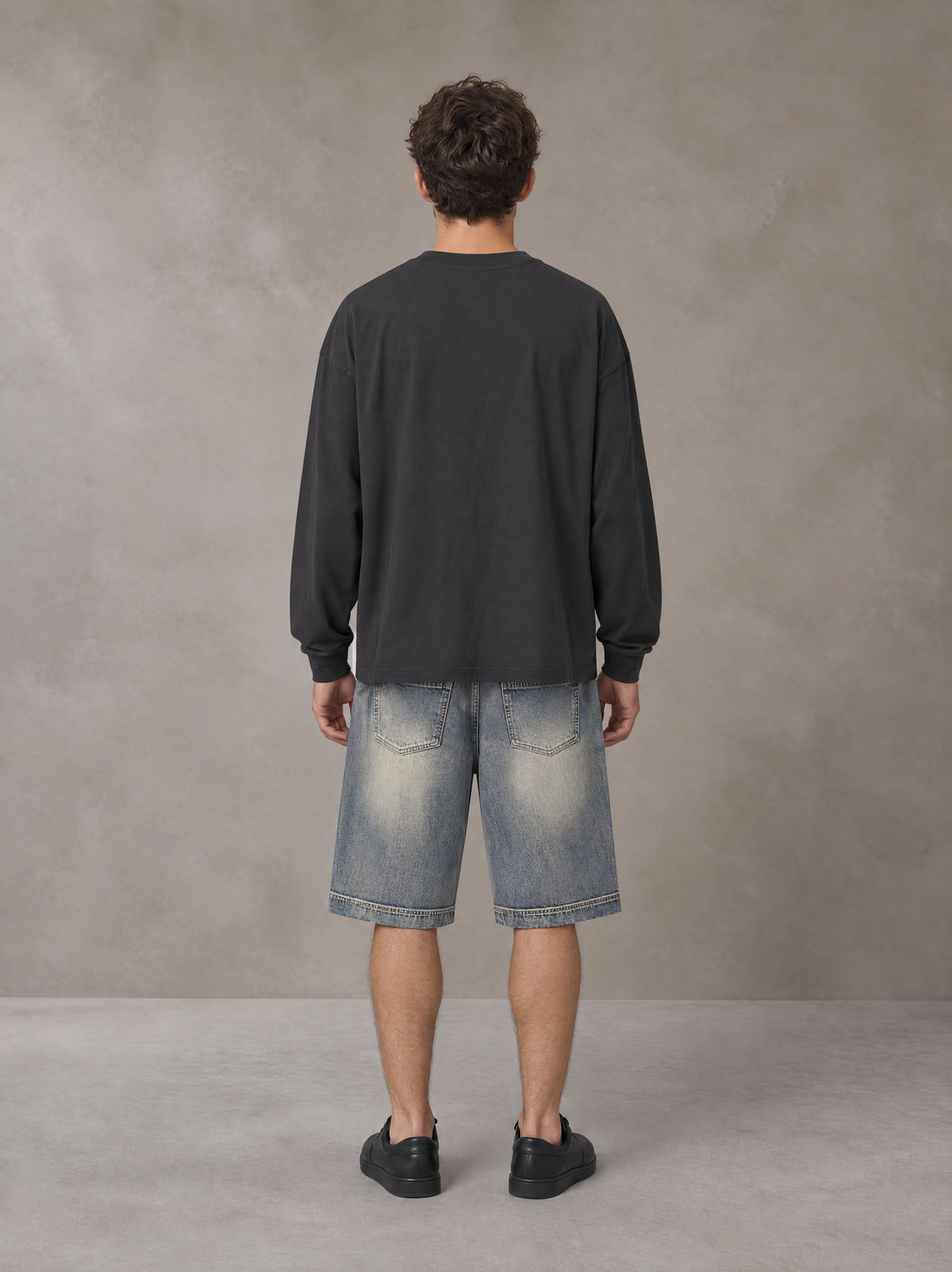 Model wearing SM Sig. Long Sleeve T-shirt in Deep Charcoal, rear view.