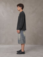 Model wearing SM Sig. Long Sleeve T-shirt in Deep Charcoal, side profile.