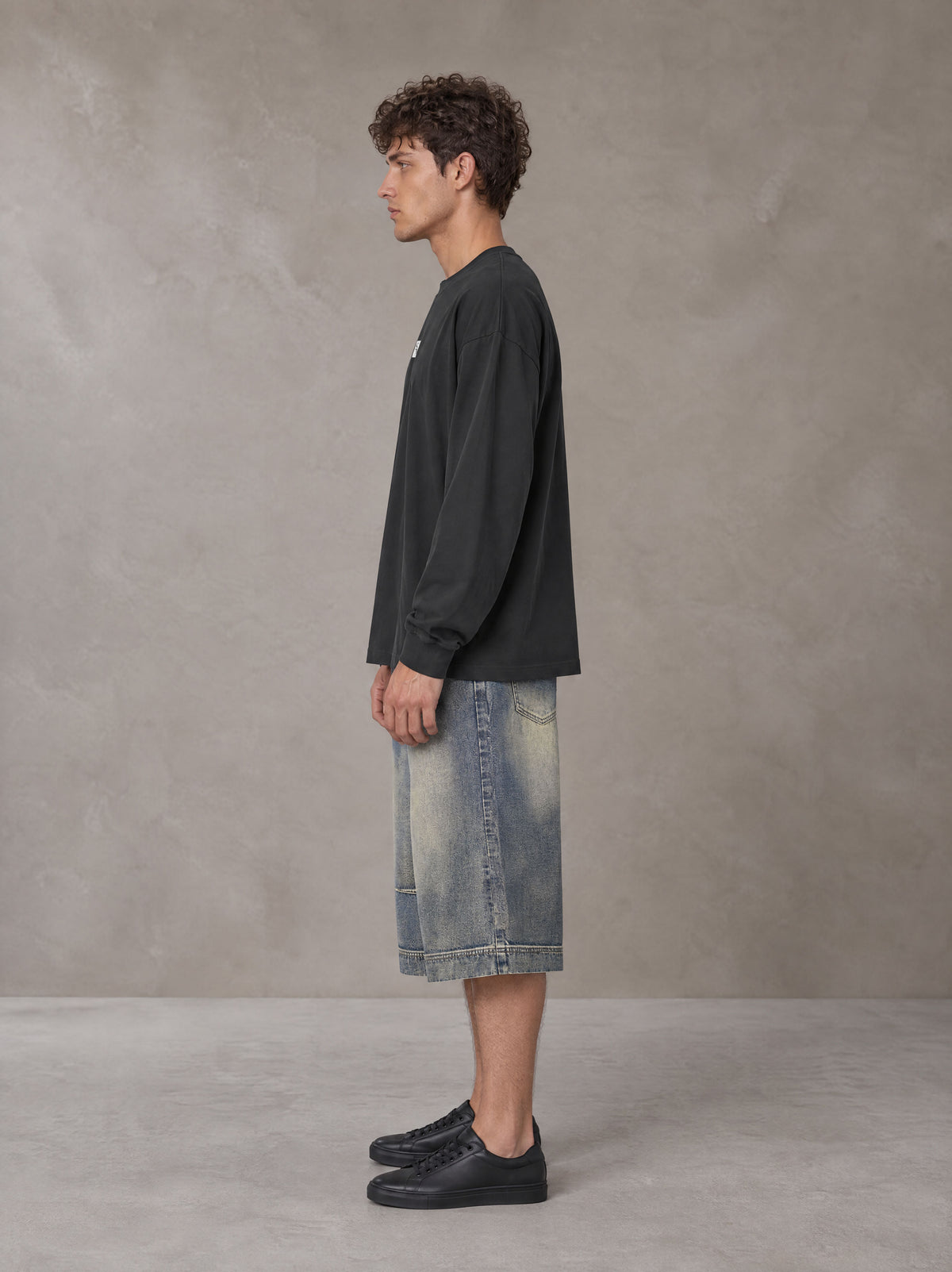 Model wearing SM Sig. Long Sleeve T-shirt in Deep Charcoal, side profile.