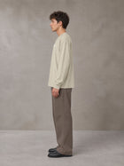 Model wearing SM Sig. Long Sleeve T-shirt in Fine Sand, side profile.