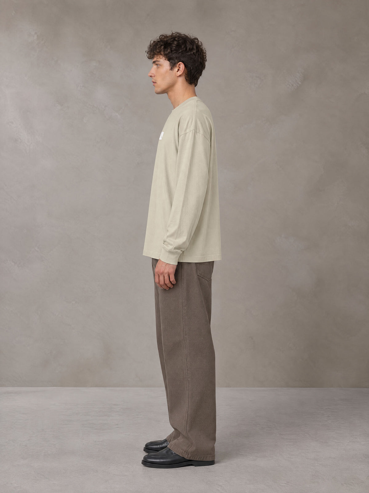 Model wearing SM Sig. Long Sleeve T-shirt in Fine Sand, side profile.