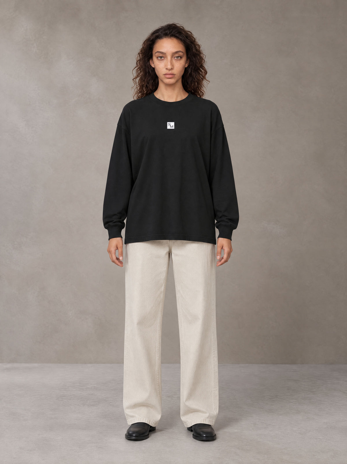 Model wearing SM Sig. Long Sleeve T-shirt in Midnight Black, front view.