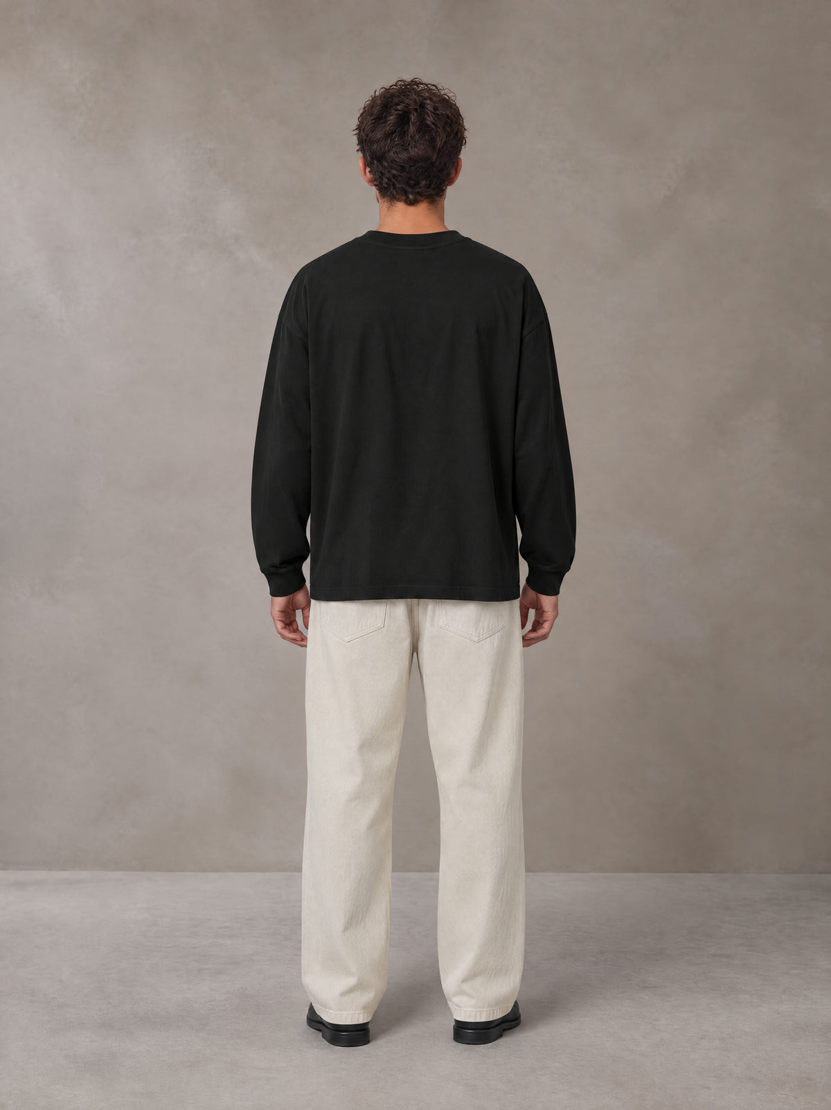 Model wearing SM Sig. Long Sleeve T-shirt in Midnight Black, rear view.