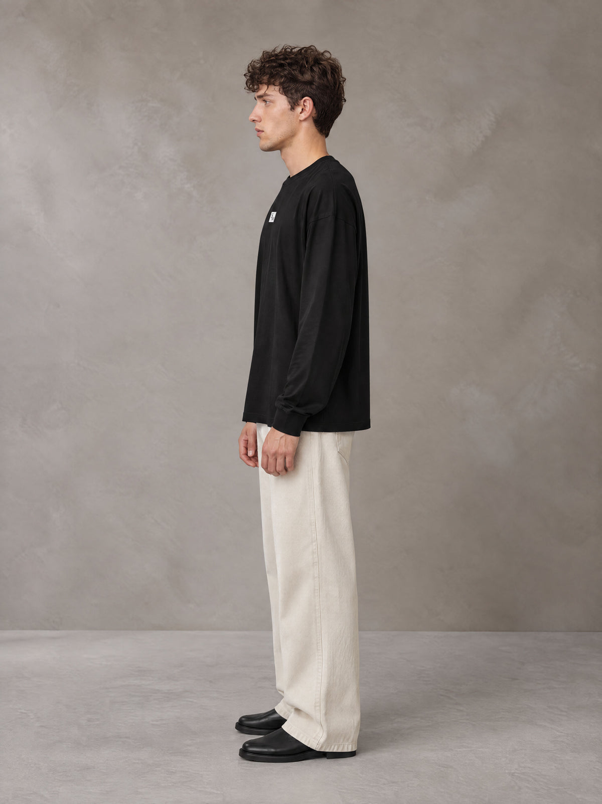 Model wearing SM Sig. Long Sleeve T-shirt in Midnight Black, side profile.