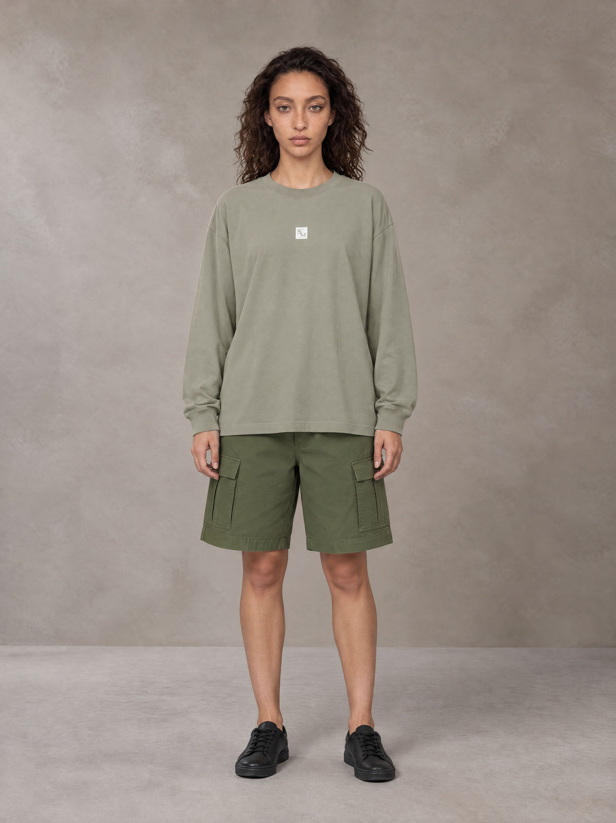 Model wearing SM Sig. Long Sleeve T-shirt in Stone Grey, front view.