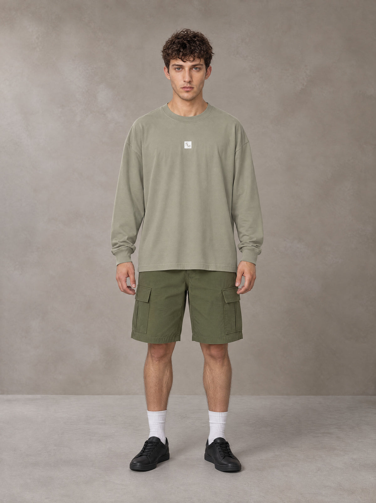 Model wearing SM Sig. Long Sleeve T-shirt in Stone Grey, front view.