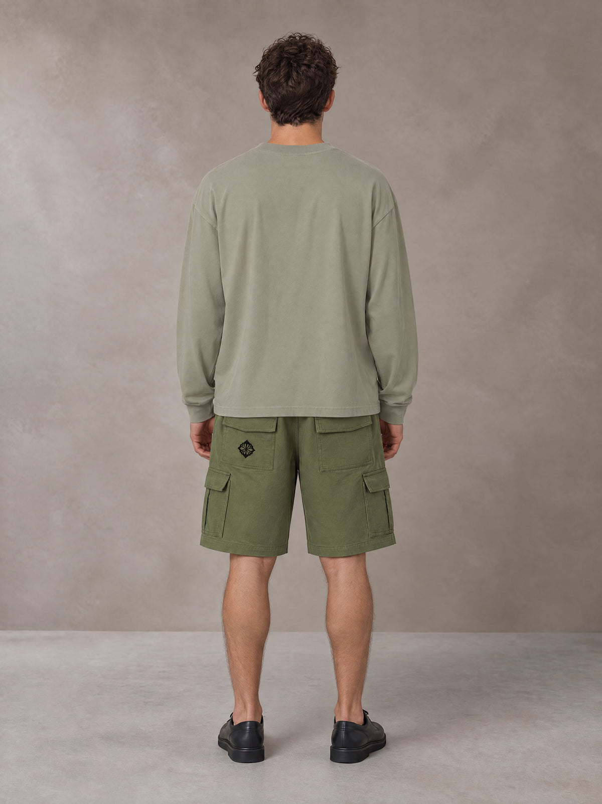 Model wearing SM Sig. Long Sleeve T-shirt in Stone Grey, rear view.