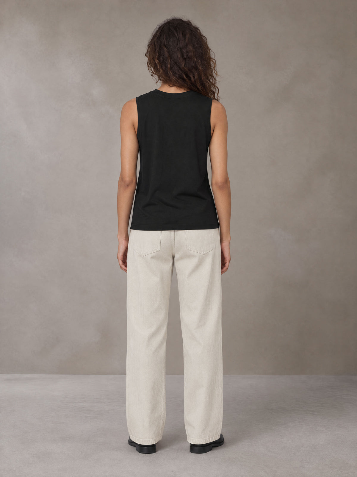Model wearing SM Sig. Sleeveless Tank Top in Midnight Black, rear view.