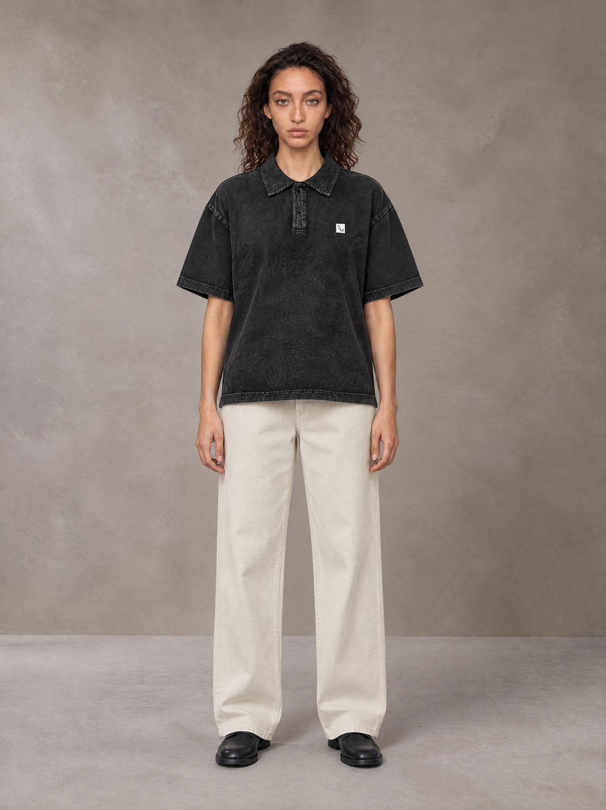 Model wearing SM Sig. Snow Washed Polo T-shirt in Midnight Black, front view.