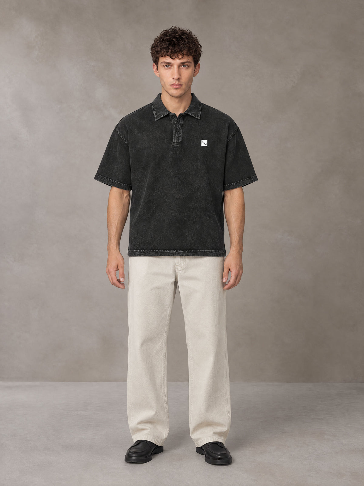 Model wearing SM Sig. Snow Washed Polo T-shirt in Midnight Black, front view.