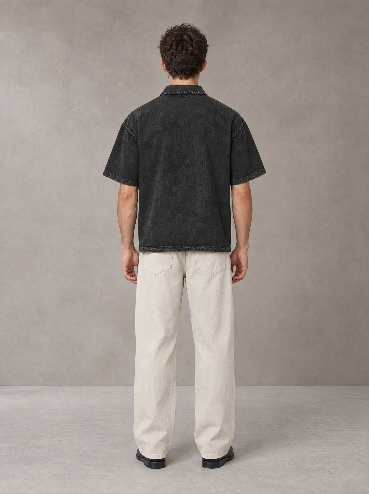 Model wearing SM Sig. Snow Washed Polo T-shirt in Midnight Black, rear view.
