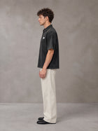 Model wearing SM Sig. Snow Washed Polo T-shirt in Midnight Black, side profile.