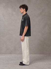 Model wearing SM Sig. Snow Washed Polo T-shirt in Midnight Black, side profile.