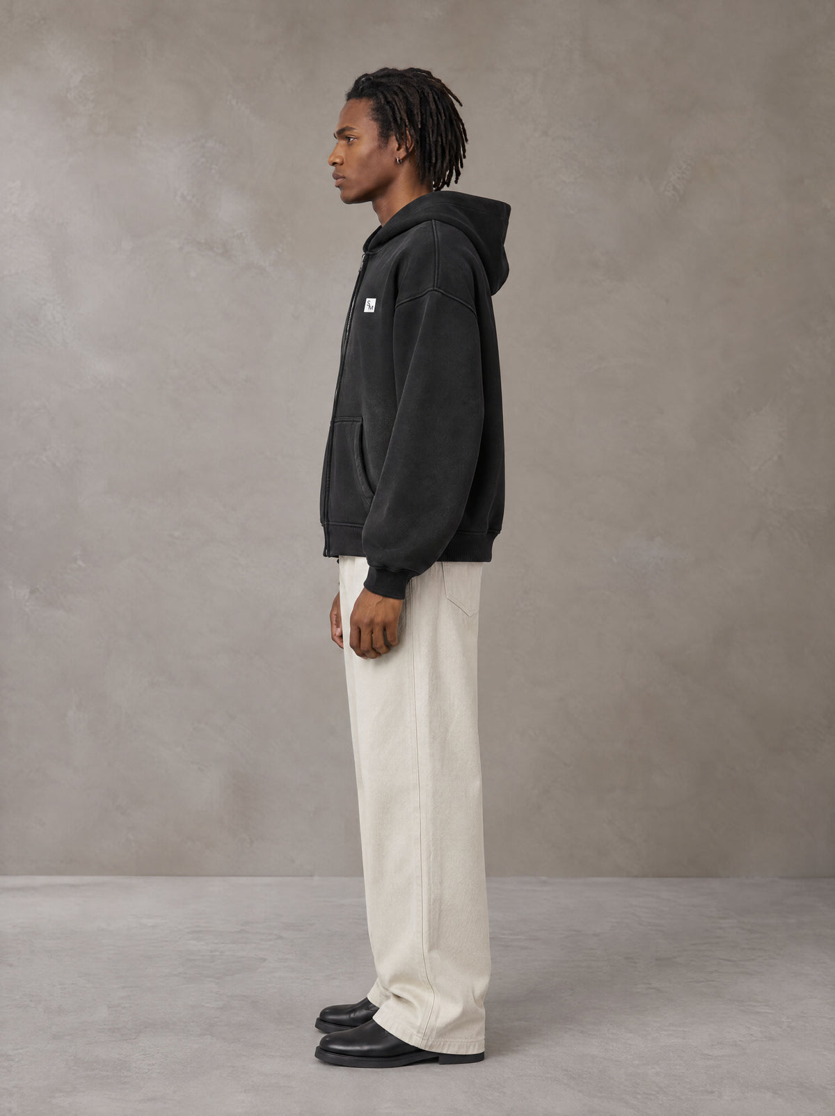 Model wearing SM Sig. Washed Boxy Hoodie in Midnight Black, side profile.