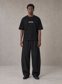 Model wearing SM Silk Logo T-shirt in Midnight Black, front view.