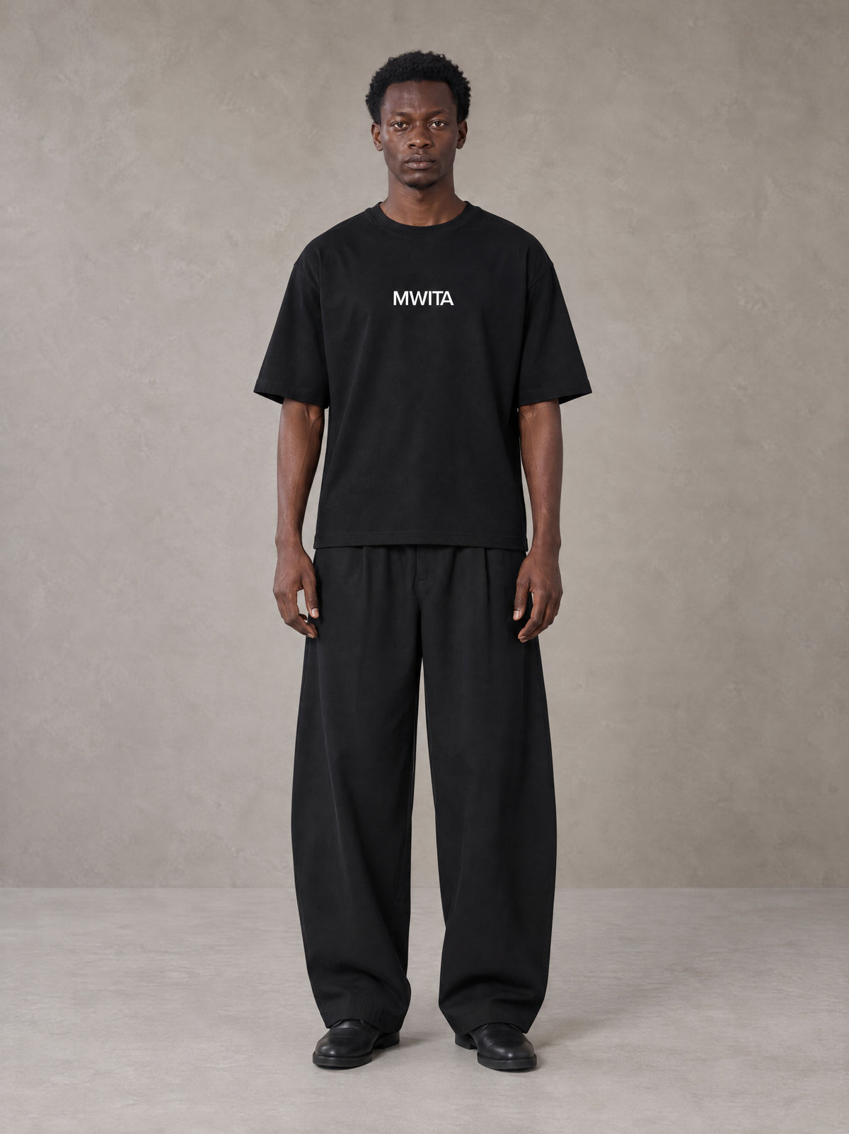 Model wearing SM Silk Logo T-shirt in Midnight Black, front view.