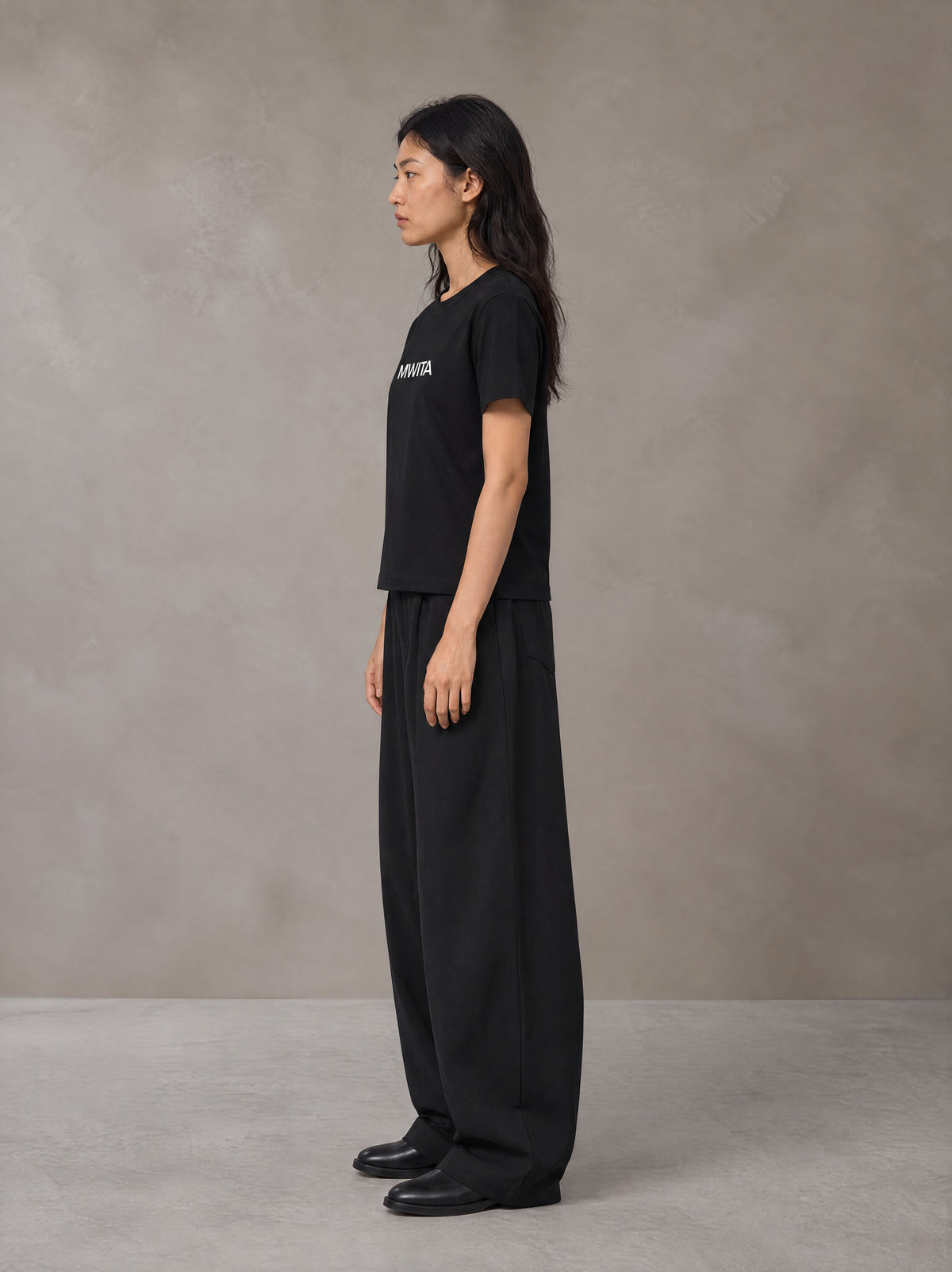 Model wearing SM Silk Logo T-shirt in Midnight Black, side profile.