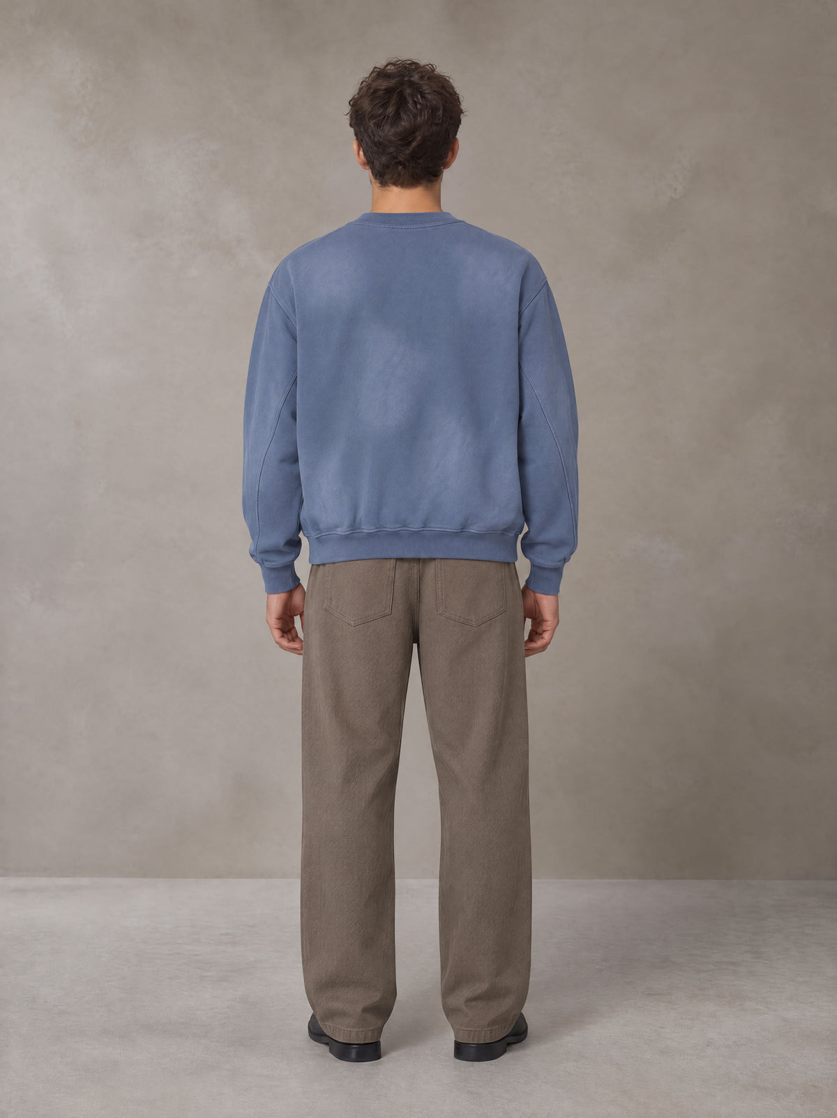 Model wearing SM Sunfade Fleeced Sweatshirt in Deep Denim, rear view.