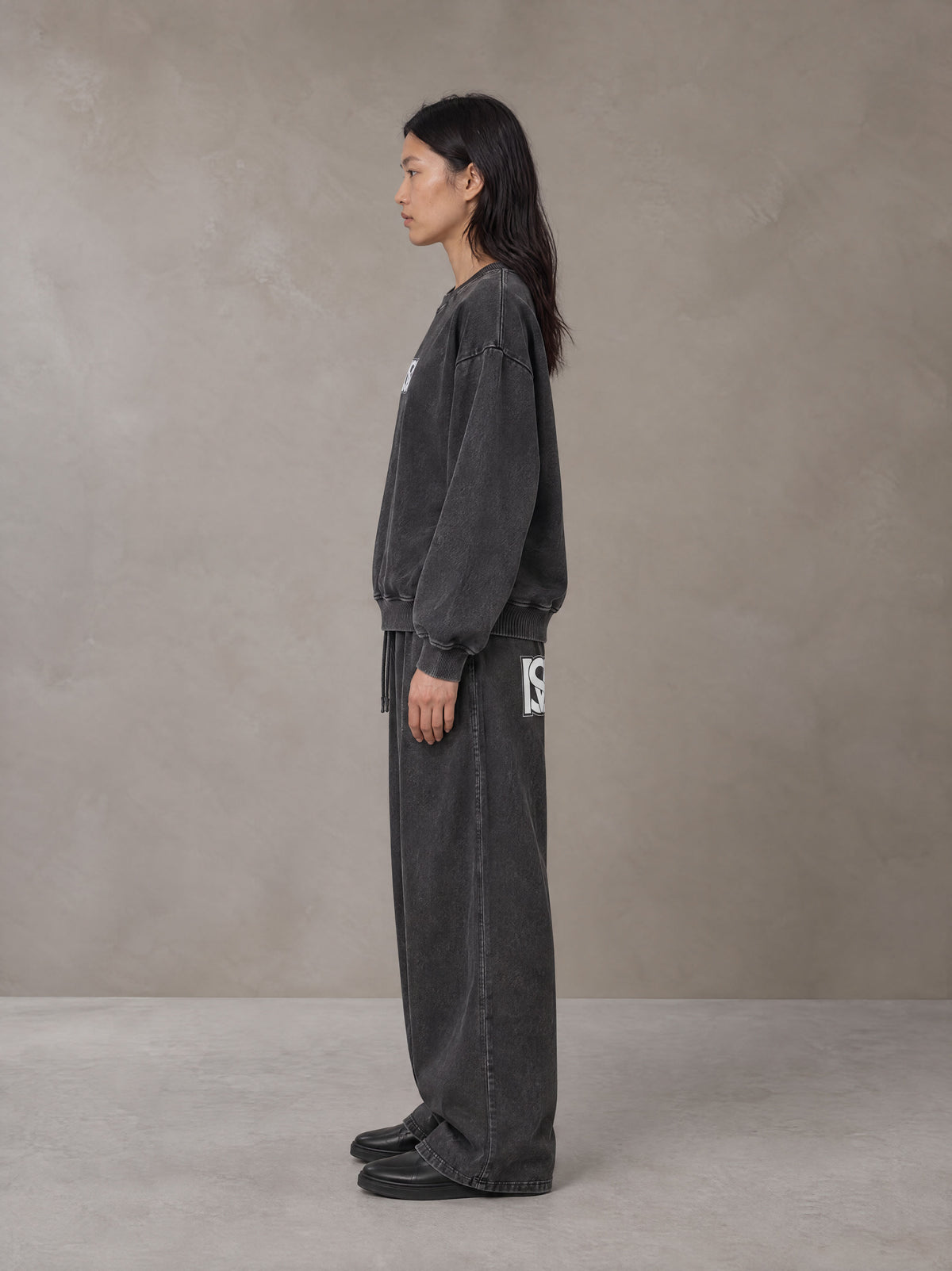 Model wearing the SM Acid Wash Sweatshirt and SM Acid Wash Trousers in Midnight Black, side profile.