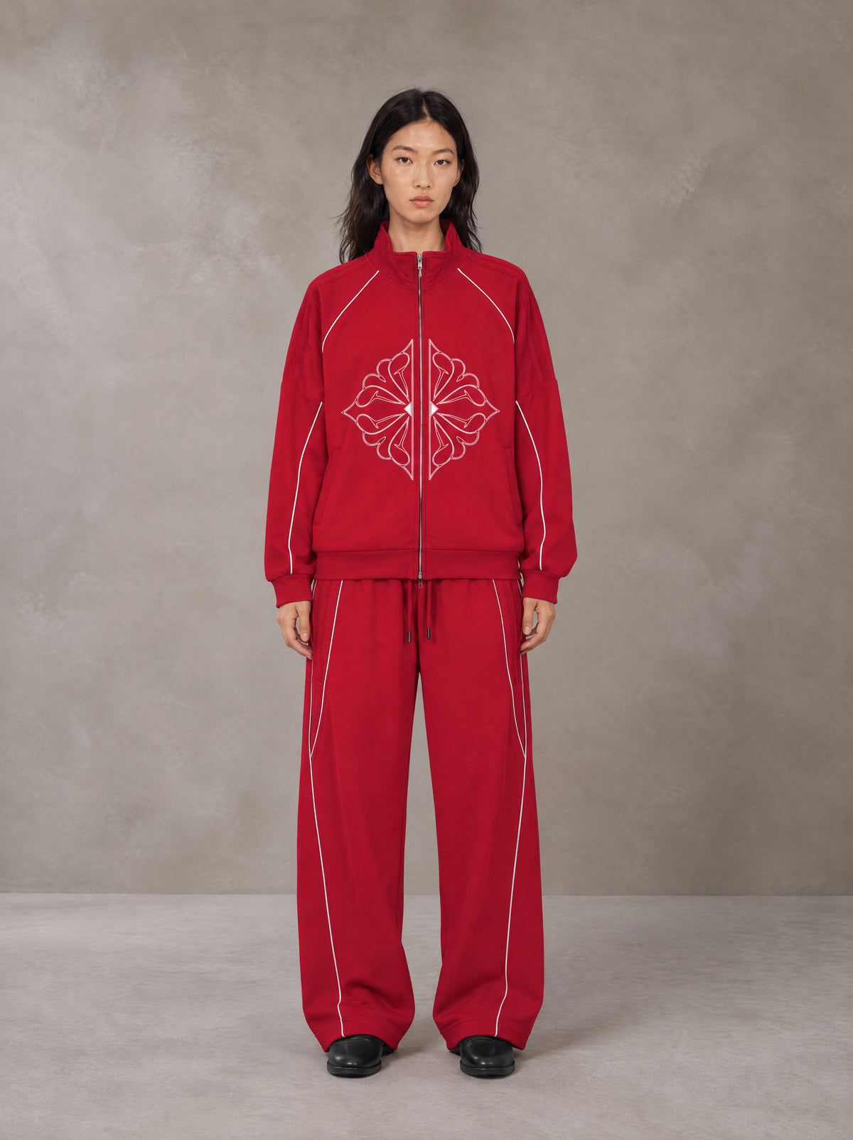 Model wearing the SM Fleur Eclipse Jacket and SM Fleur Eclipse Sweatpants in Crimson, front view.