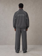 Model wearing the SM Fleur Eclipse Jacket and SM Fleur Eclipse Sweatpants in Deep Charcoal, rear view.