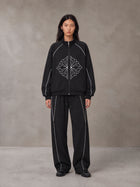 Model wearing the SM Fleur Eclipse Jacket and SM Fleur Eclipse Sweatpants in Midnight Black, front view.