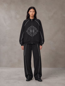 Model wearing the SM Fleur Eclipse Jacket and SM Fleur Eclipse Sweatpants in Midnight Black, front view.