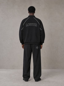 Model wearing the SM Fleur Eclipse Jacket and SM Fleur Eclipse Sweatpants in Midnight Black, rear view.