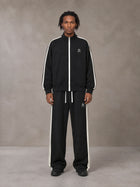 Model wearing the SM Insignia Track Jacket and SM Insignia Track Trousers in Midnight Black, front view.