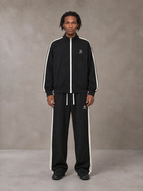 Model wearing the SM Insignia Track Jacket and SM Insignia Track Trousers in Midnight Black, front view.