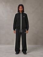 Model wearing the SM Insignia Track Jacket and SM Insignia Track Trousers in Midnight Black, front view.