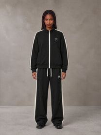 Model wearing the SM Insignia Track Jacket and SM Insignia Track Trousers in Midnight Black, front view.