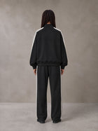 Model wearing the SM Insignia Track Jacket and SM Insignia Track Trousers in Midnight Black, rear view.