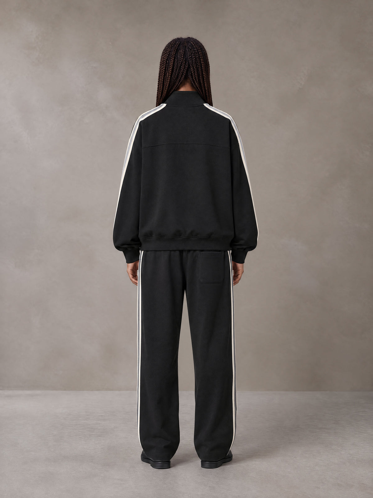 Model wearing the SM Insignia Track Jacket and SM Insignia Track Trousers in Midnight Black, rear view.