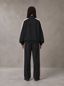 Model wearing the SM Insignia Track Jacket and SM Insignia Track Trousers in Midnight Black, rear view.