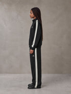 Model wearing the SM Insignia Track Jacket and SM Insignia Track Trousers in Midnight Black, side profile.