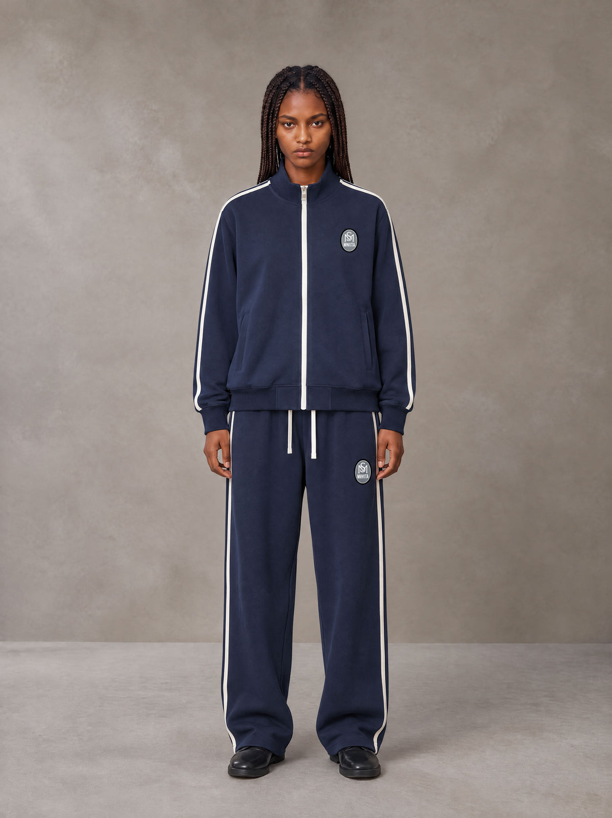 Model wearing the SM Insignia Track Jacket and SM Insignia Track Trousers in Oxford Navy, front view.