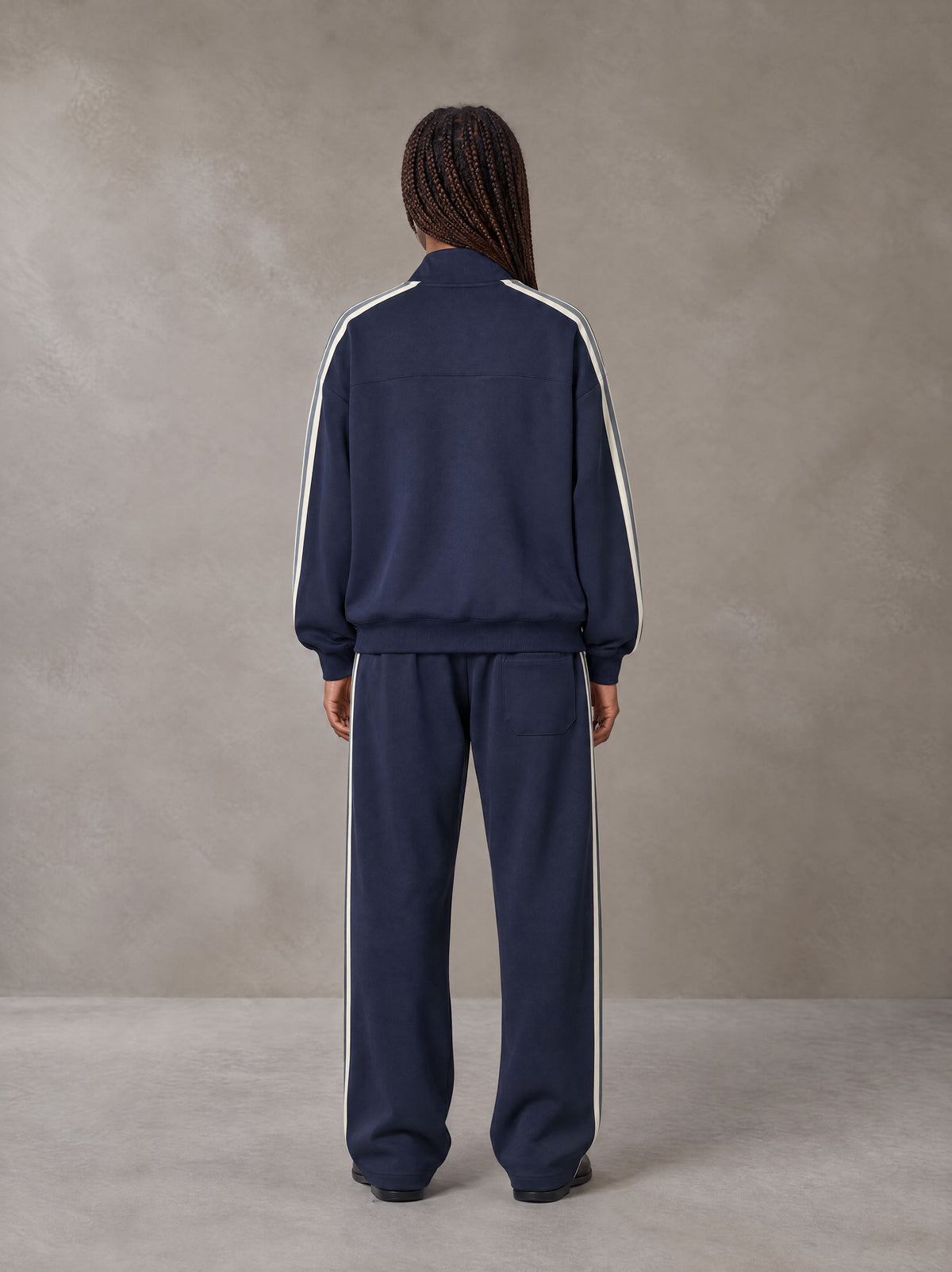 Model wearing the SM Insignia Track Jacket and SM Insignia Track Trousers in Oxford Navy, rear view.