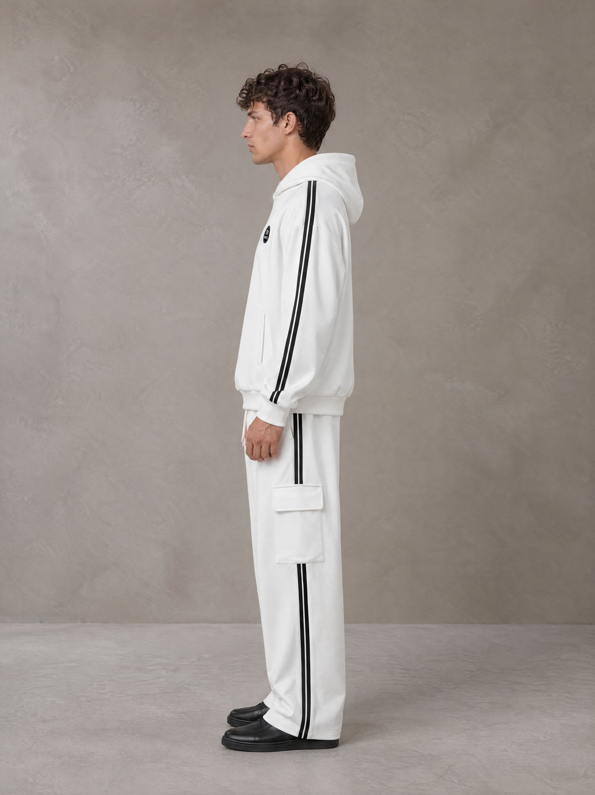 Model wearing the SM Insignia Utility Hoodie and SM Insignia Utility Sweatpants in Lucent White, side profile.