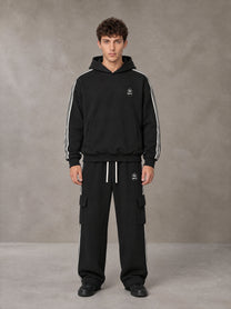 Model wearing the SM Insignia Utility Hoodie and SM Insignia Utility Sweatpants in Midnight Black, front view.