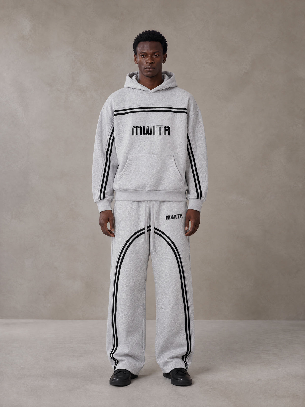 Model wearing the SM Track Line Hoodie and SM Track Line Sweatpants in Floral Grey, front view.