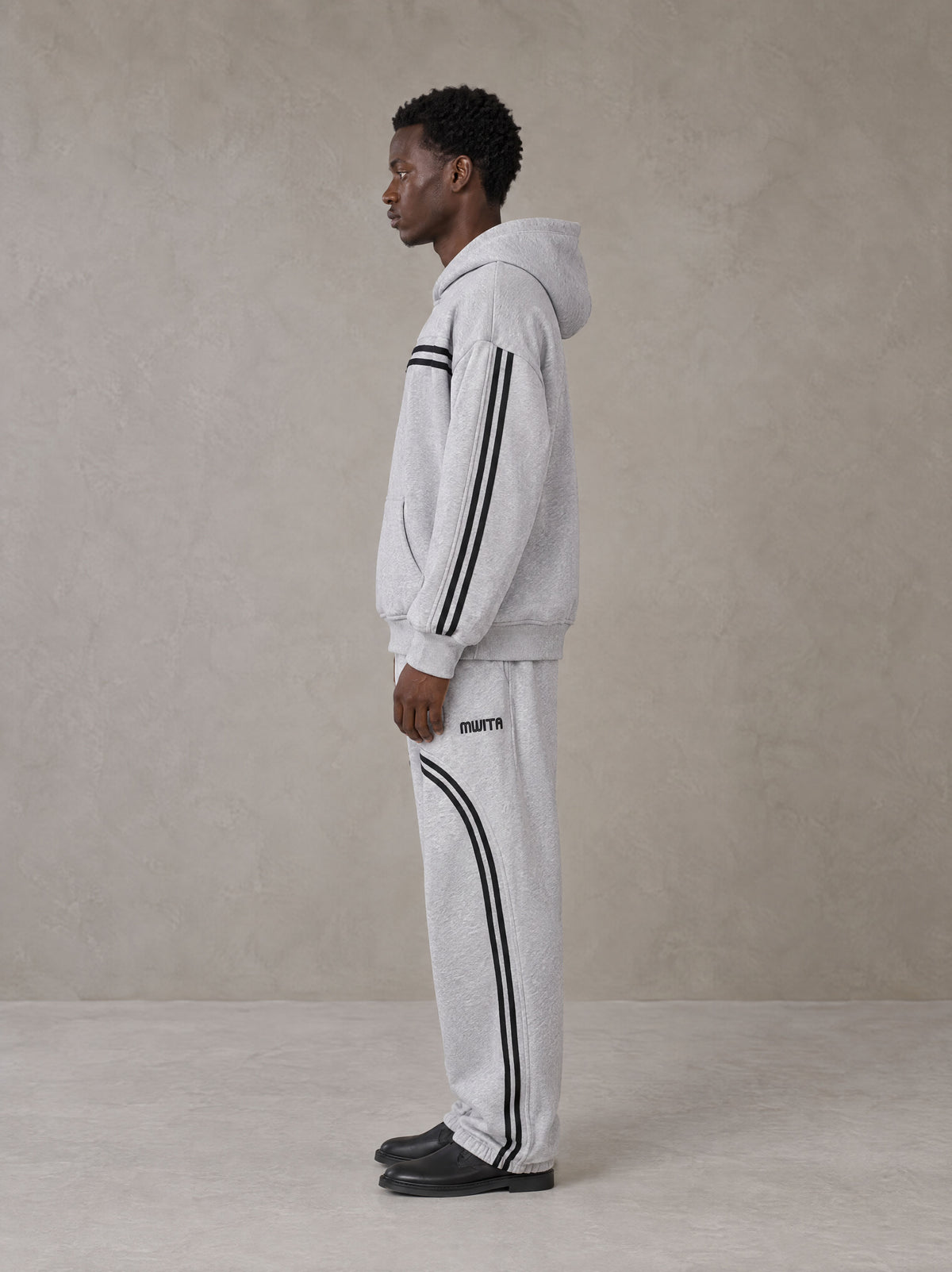 Model wearing the SM Track Line Hoodie and SM Track Line Sweatpants in Floral Grey, side profile.