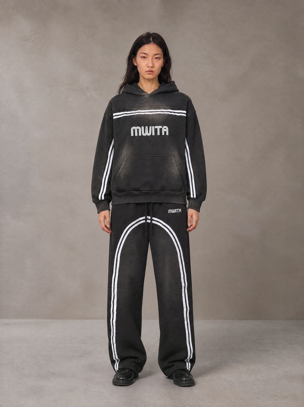 Model wearing the SM Track Line Hoodie and SM Track Line Sweatpants in Midnight Black, front view.