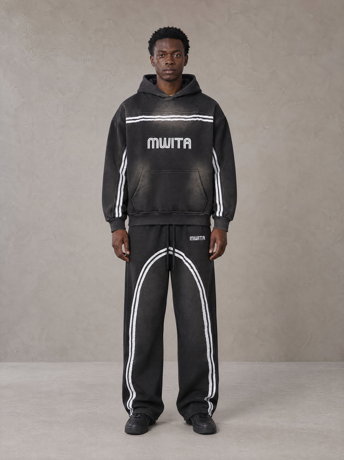 Model wearing the SM Track Line Hoodie and SM Track Line Sweatpants in Midnight Black, front view.