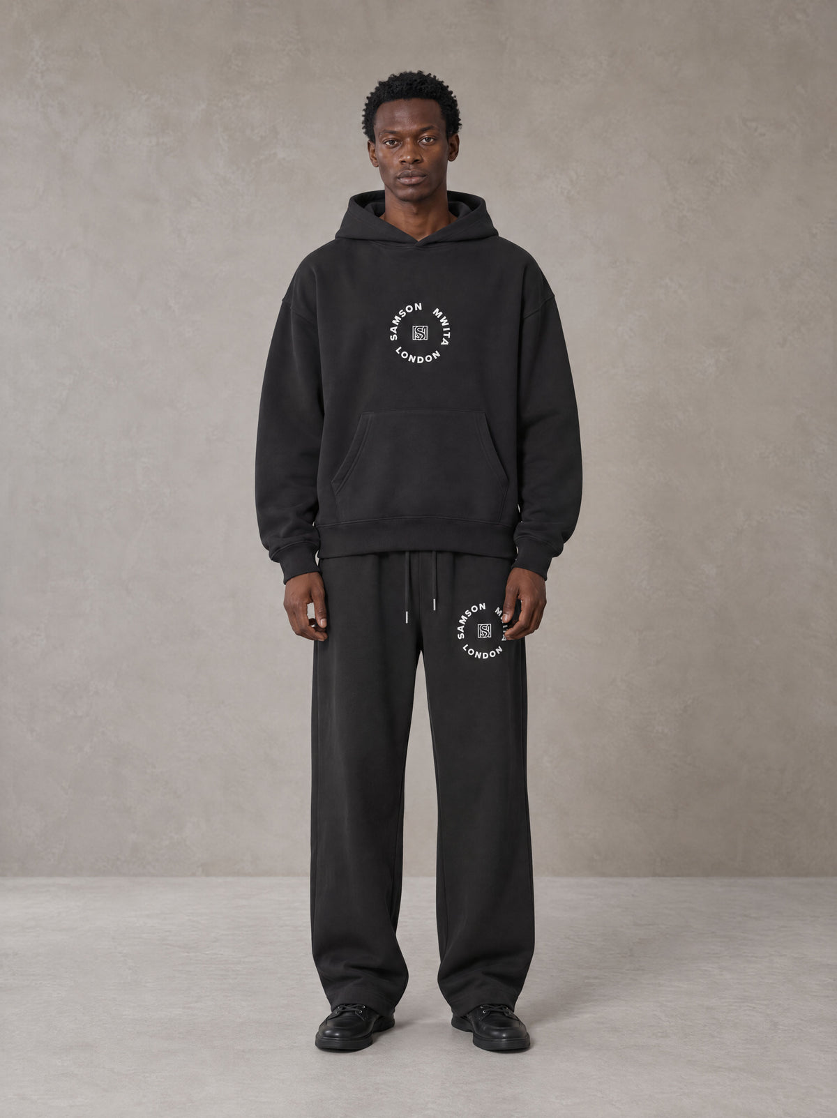 Model wearing the SM London Hoodie and SM London Sweatpants in Deep Charcoal, front view.