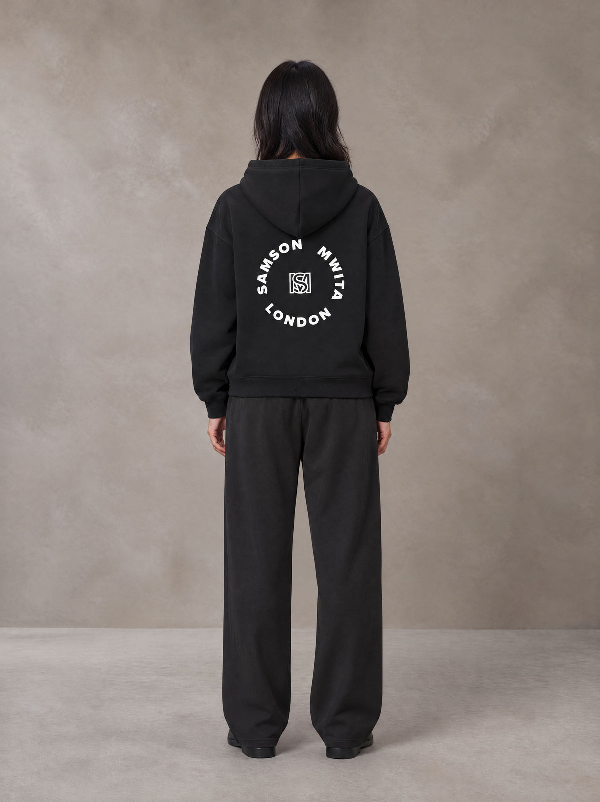 Model wearing the SM London Hoodie and SM London Sweatpants in Deep Charcoal, rear view.