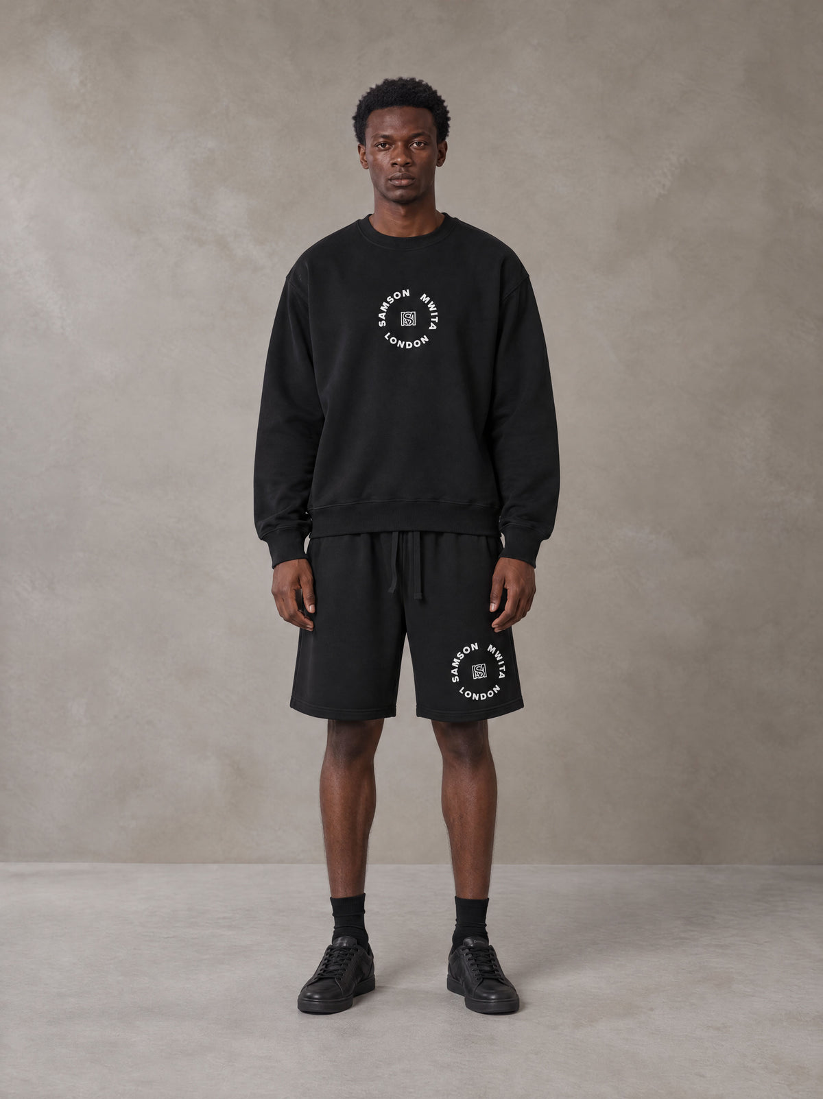 Model wearing the SM London Sweatshirt and SM London Shorts in Midnight Black, front view.