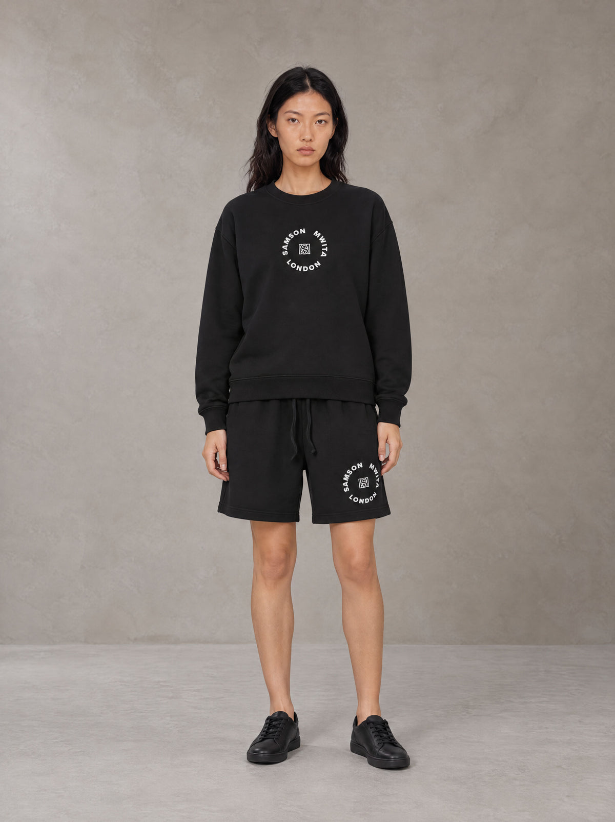 Model wearing the SM London Sweatshirt and SM London Shorts in Midnight Black, front view.