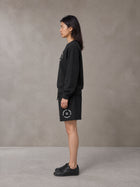 Model wearing the SM London Sweatshirt and SM London Shorts in Midnight Black, side profile.