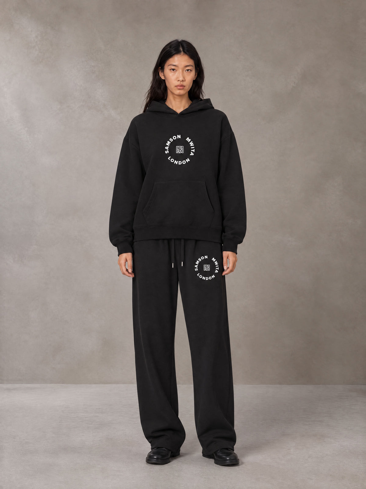 Model wearing the SM London Hoodie and SM London Sweatpants in Midnight Black, front view.
